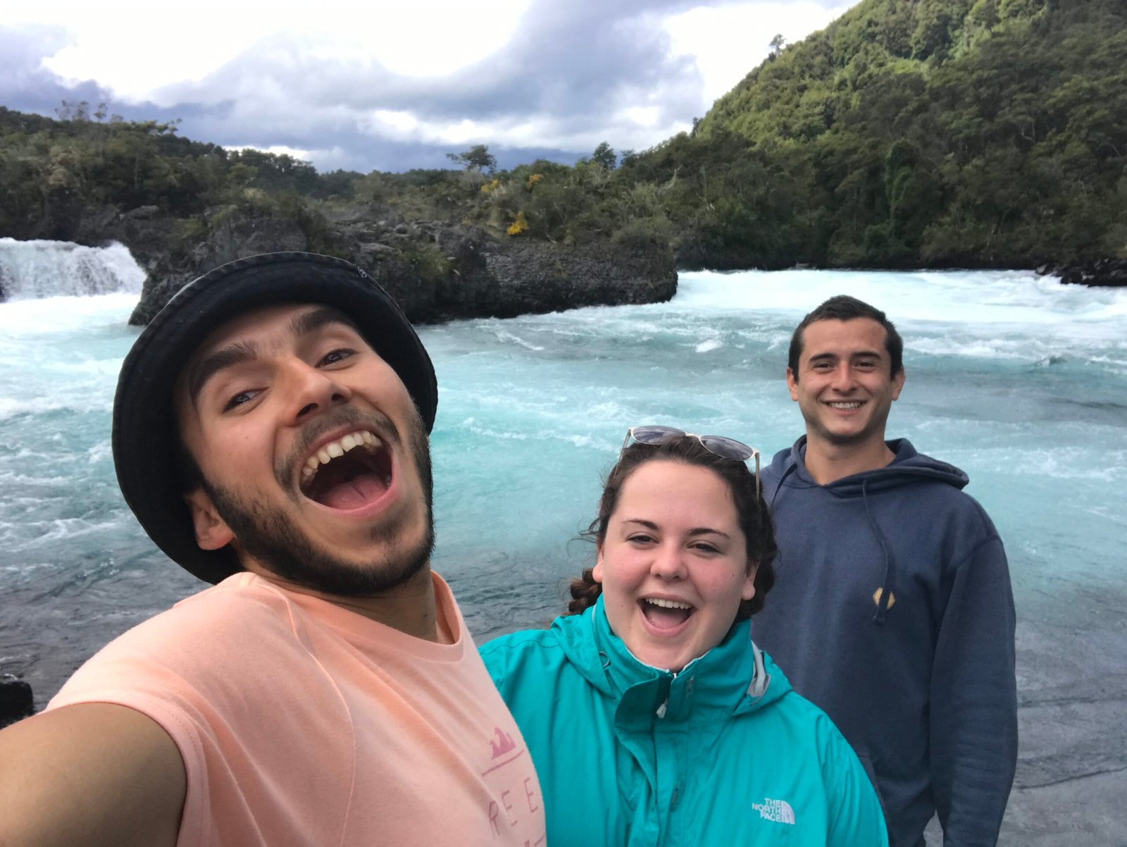Maestre Paige stands with two young men on a hike, everyone is smiling with wide mouths.